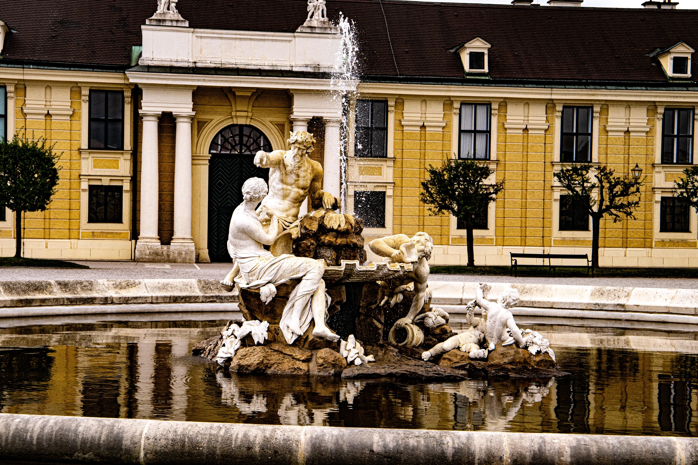 The Neptune Fountain before the yellow facade of Schonbrunn Palace in Vienna.