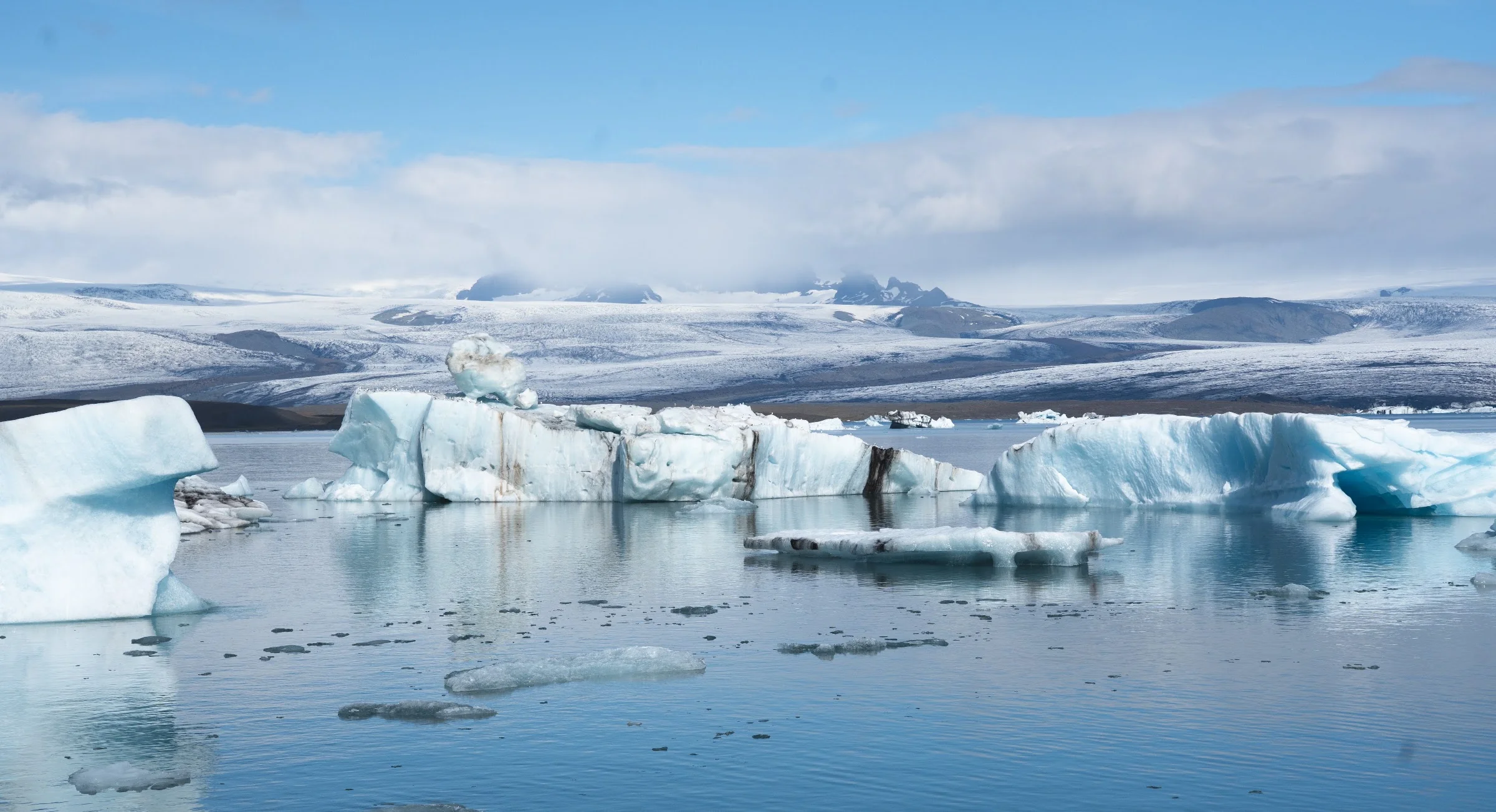 Icebergs reflected across the surface of a glacial lagoon.
