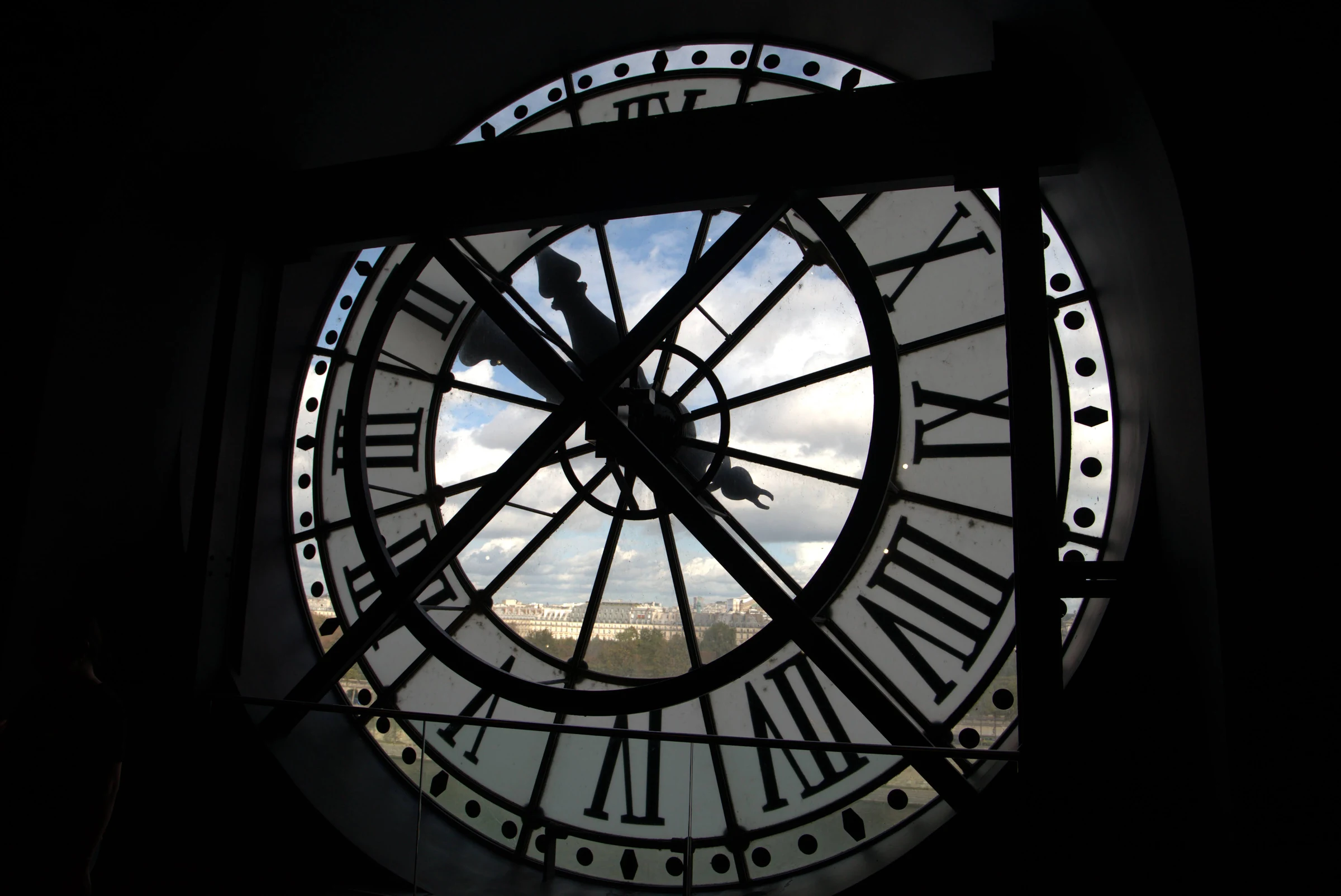The backlit Roman-numeral clock at Musee d'Orsay framing the Paris skyline.