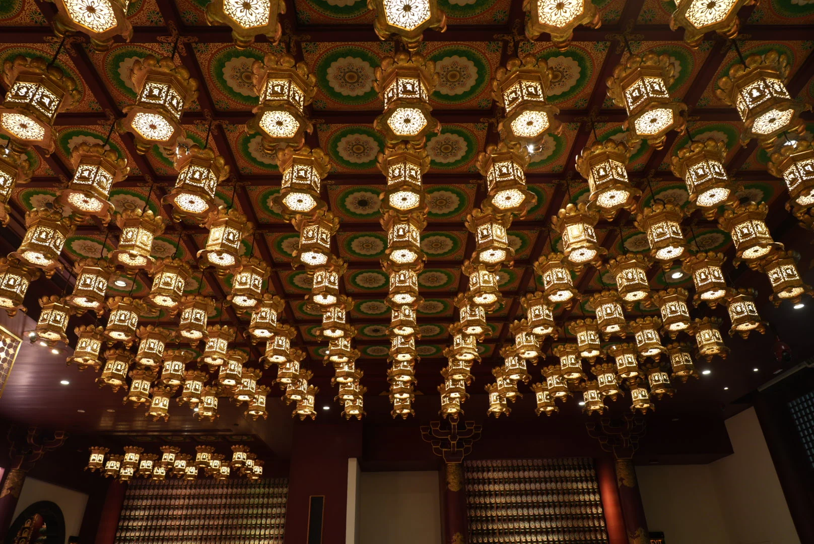 Rows of glowing lotus lanterns beneath the decorated ceiling of Singapore's Buddha Tooth Relic Temple.