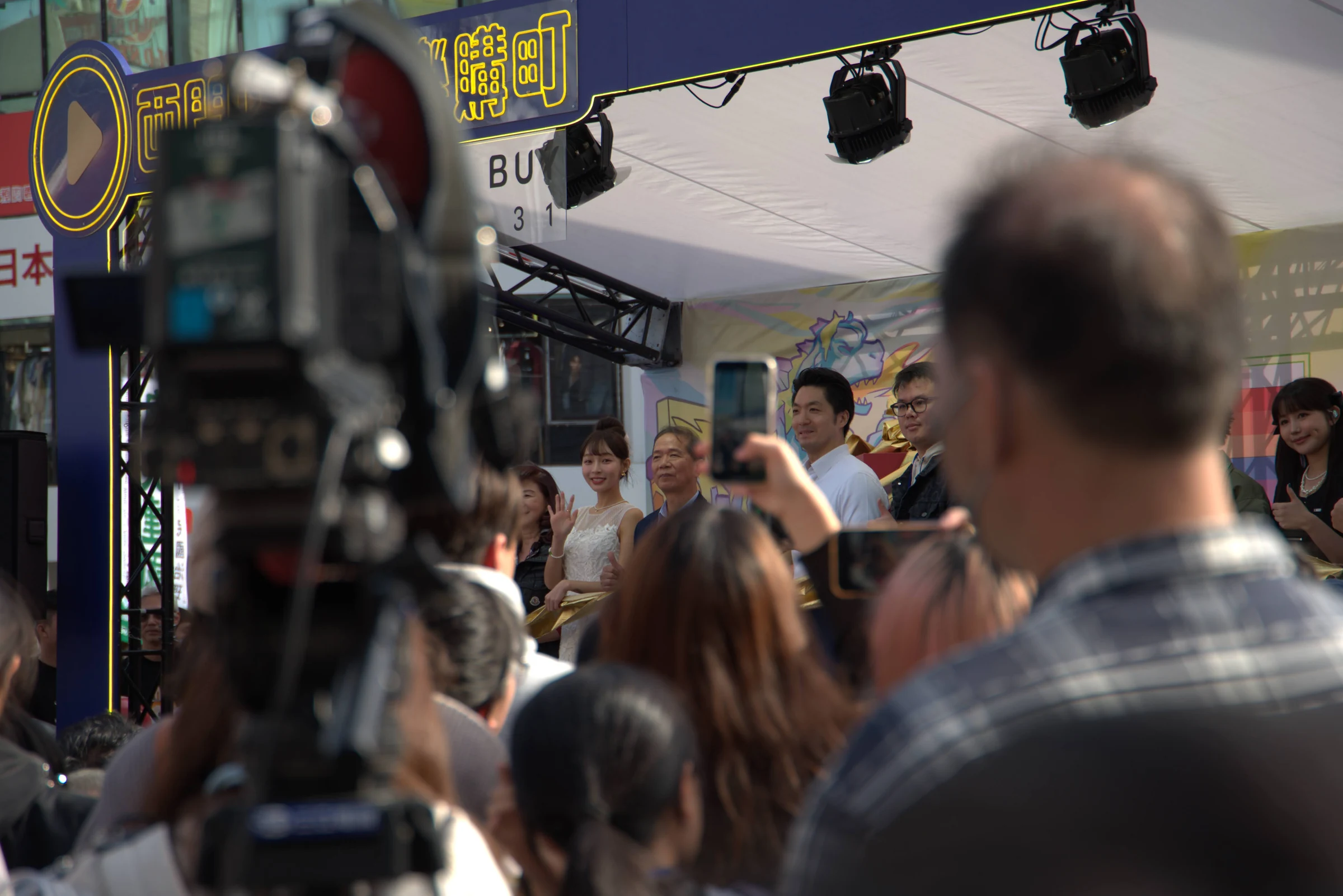 Cameras and spectators surrounding guests at an outdoor promotional event in Ximending.
