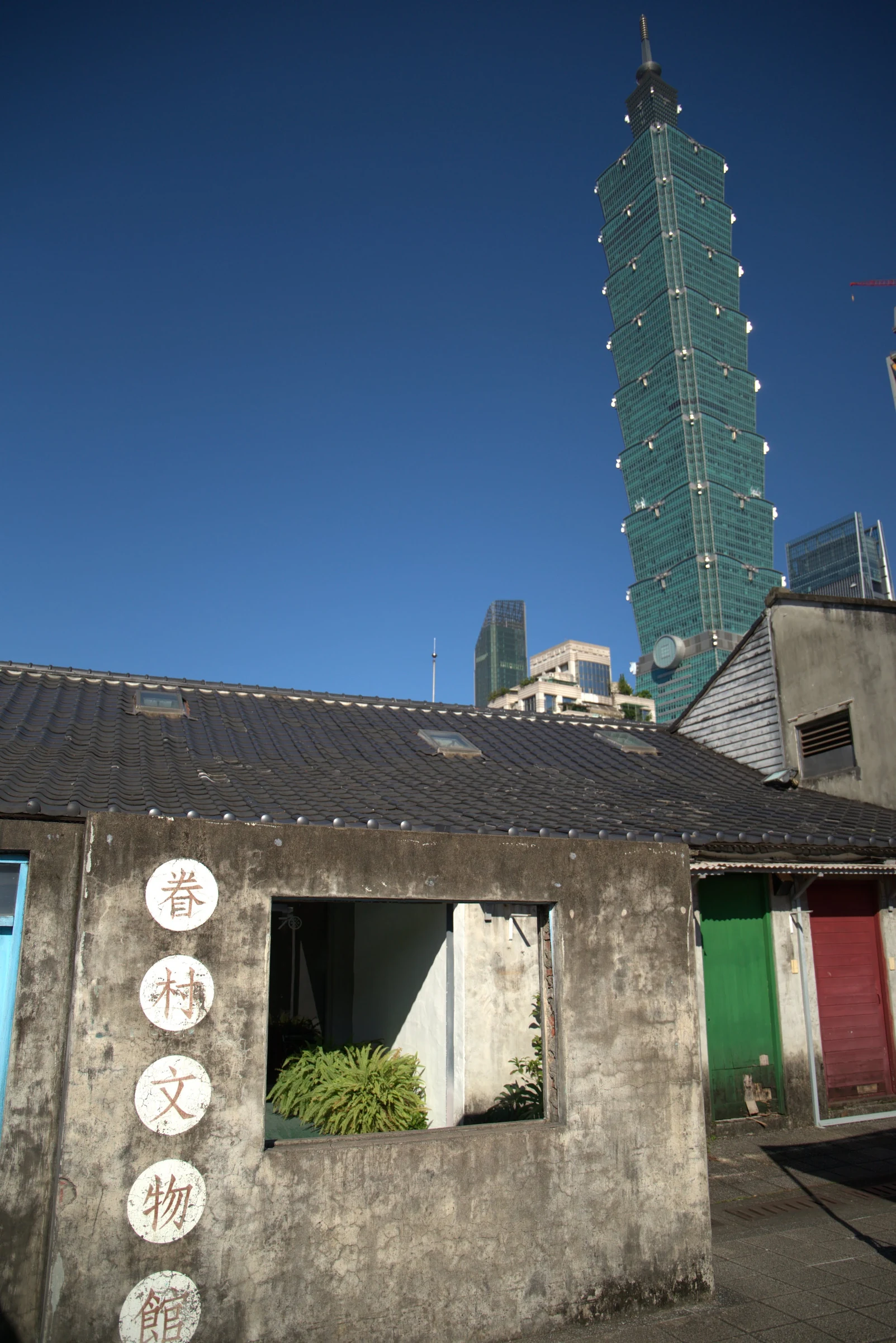 Taipei 101 rising behind the preserved houses of Four Four South Village.
