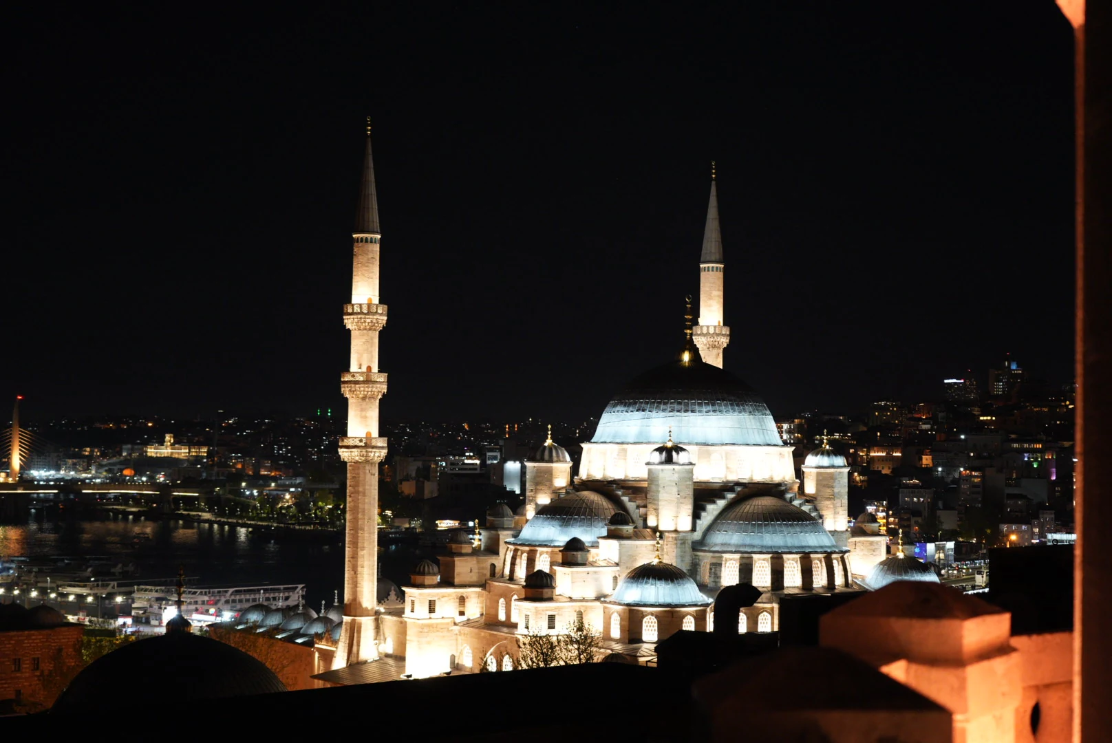 An illuminated Ottoman mosque beside the Golden Horn at night in Istanbul.