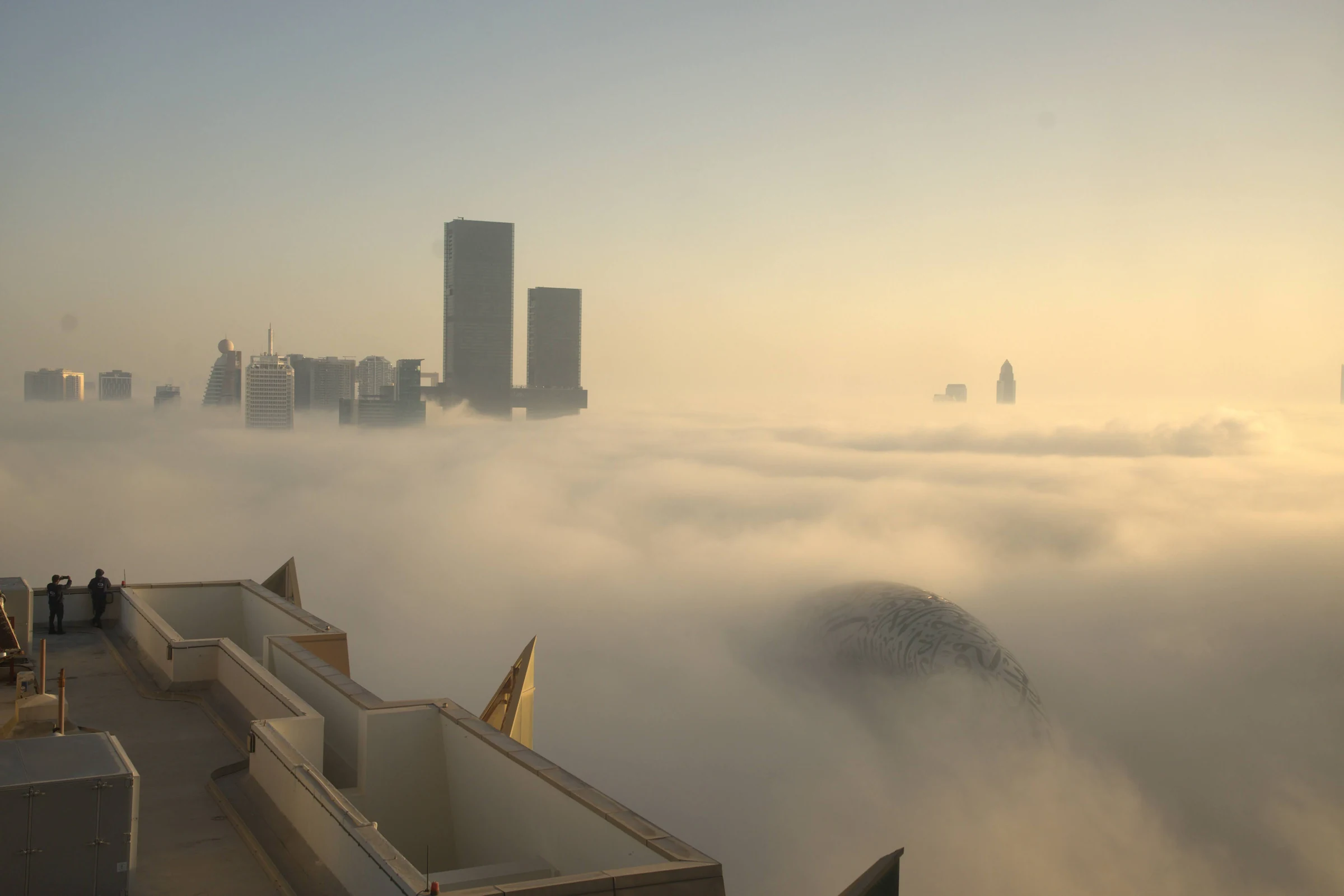 Dubai towers and the Museum of the Future emerging through golden fog.